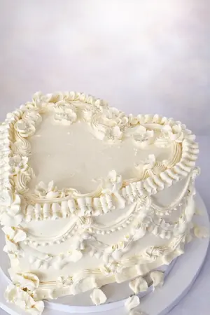 White heart-shaped vintage cake with cream piping